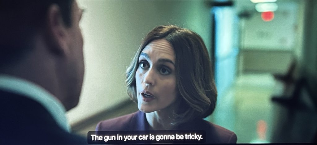 Screen capture from Your Friends & Neighbors season 1 episode 8. Kat Resnick, portrayed by Heather Lind, speaks to Andrew Cooper in a courthouse hallway. Close-up of her face with a serious, intent expression, shoulder-length hair parted at the center, wearing a dark blazer. Subtitle reads βThe gun in your car is gonna be tricky.β
Alt text by ALT Text Artist GPT